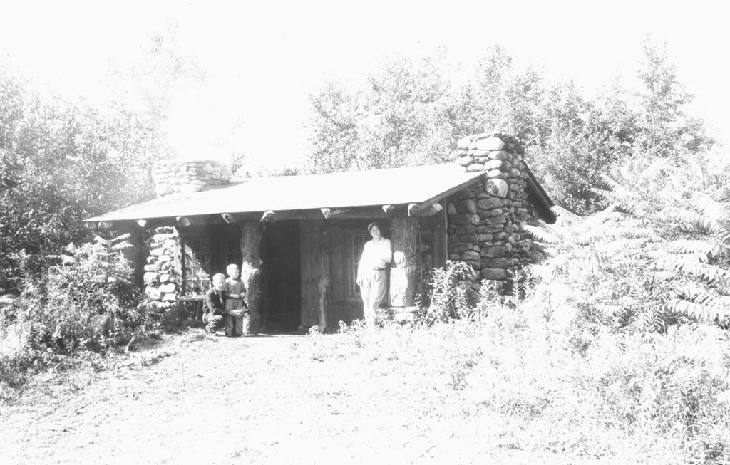 Miniature of Two adults and a child outside a lodge